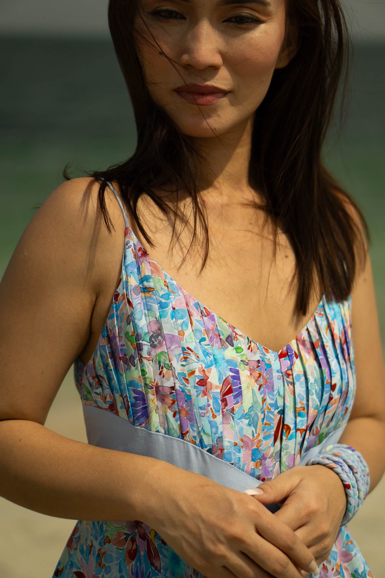In this close up image, the dress is sleeveless with straps and the neck line is a deep V. The top panel is of blue floral fabric, this panel of fabric consists of tucks which creates a 3D look at the chest, giving an attractive look!