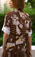 Back view of printed brown shirt dress with side slits, women’s full-length button-down shirt dress featuring artistic script print and short sleeves
