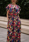 Women wearing a retro V-neck A-line maxi dress with bold printed design. The dress also consist of pockets!